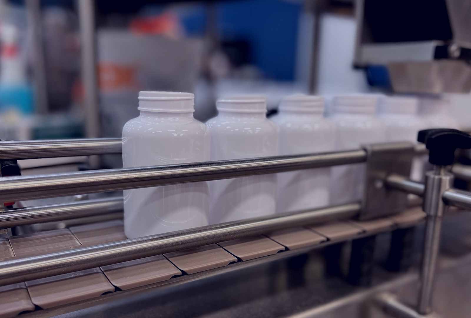 Lightning Labs manufacturing bottles on an assembly line, feeding through a hopper that dispenses capsules.